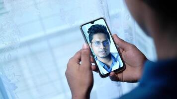 A man is holding a smartphone with a call on it video
