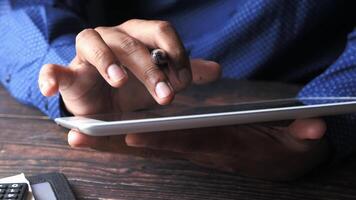Man using tablet computer and pen on wooden table video