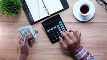 Businessman's hands calculating money with calculator and money on table video