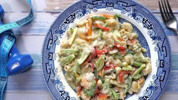 A plate of pasta with vegetables and a measuring tape video