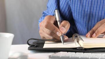 A man is writing in a notebook with a pen video
