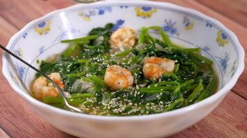 A bowl of soup with shrimp and spinach video