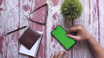 Man using smartphone with green screen on wooden table video