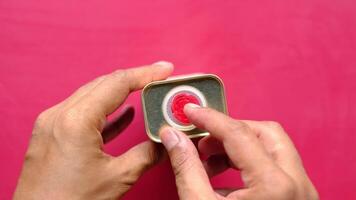 A person holding a small red button on a pink background video