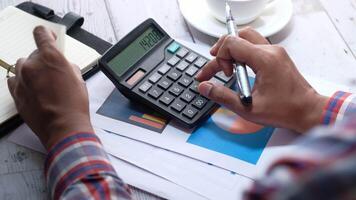 Businessman using calculator on desk with notebook and pen video