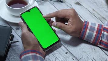 Man using smartphone with green screen on wooden table video