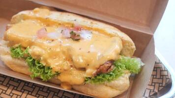 A hot dog with cheese and lettuce in a container video