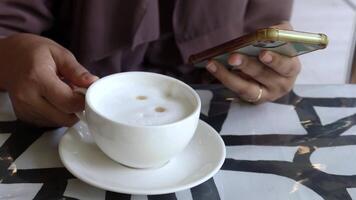 A person holding a cell phone and a cup of coffee video