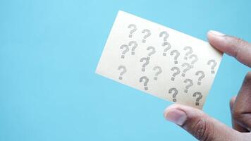 Hand holding a piece of paper with question marks on it video