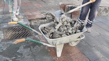 Construction workers are using a wheelbarrow on a paved surface while performing their duties video