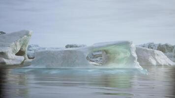 A stunning iceberg with a natural arch floating in tranquil waters at dawn video