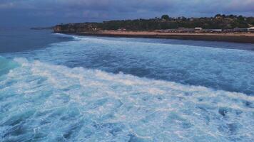 Bali coastline with ocean breaking waves and twilight tones. Drone view video