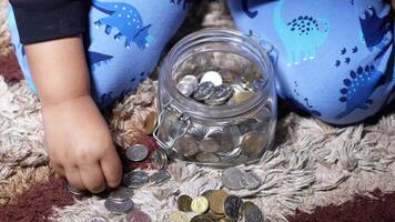 A child is sitting on the floor with coins video