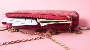 A red purse with money and credit cards on a pink background video