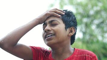A young man is holding his head while standing in the rain video