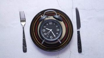A clock on a plate with a fork and knife video
