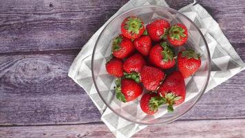 A bowl of strawberries on a wooden table video