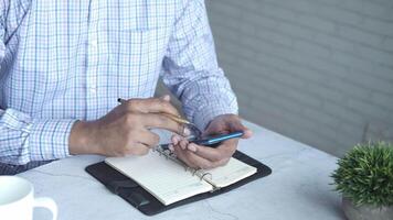 A man is using his cell phone while sitting at a table video