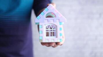 A person holding a small house with a window video