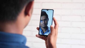 A man is using a smartphone to take a selfie with a friend video