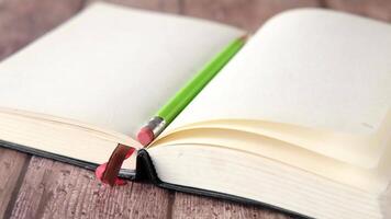 A green pencil is resting on top of an open book video