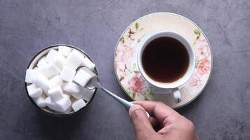 Sugar cubes in a cup and spoon on a gray background video
