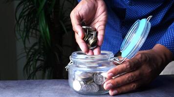 A man is putting coins into a jar video