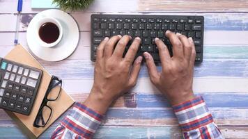 A person typing on a keyboard with a calculator and coffee cup video