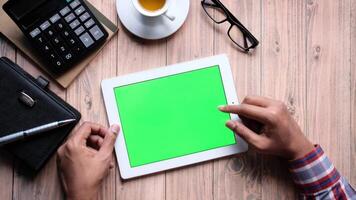 Man using tablet with green screen on wooden table video