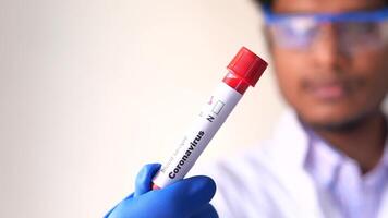 A man in a lab coat holding a tube with a red and white label video