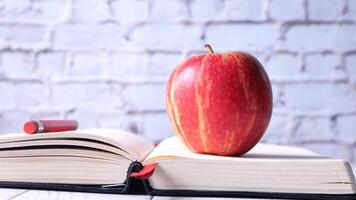 An apple is sitting on top of an open book with a pencil video