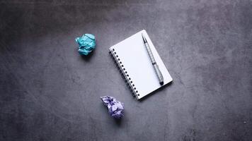 A notebook, pen and crumpled paper on a concrete surface video