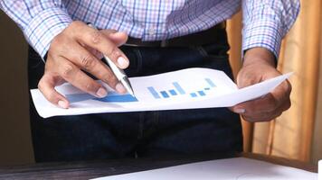 A man is holding a pen and looking at a paper with a graph on it video