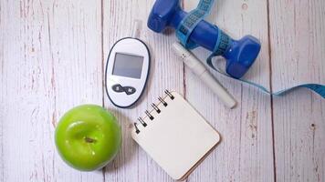 A notebook, a green apple, a pair of dumbbells and a blood glucose meter video