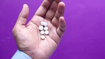 A person holding a handful of pills on a purple background video