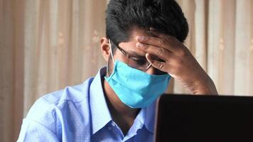 A man wearing a face mask while using a laptop video