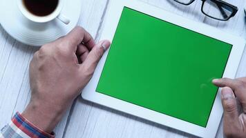 Man using tablet with green screen on wooden table video