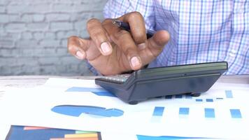 A man is using a calculator to calculate the value of a business video