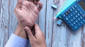 A person is holding their wrist with a calculator video