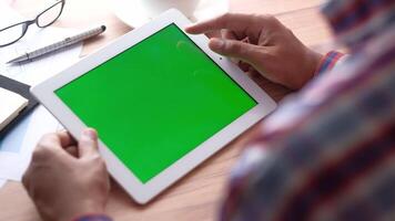 Man using tablet pc with green screen on wooden desk video