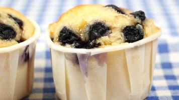 Two muffins with blueberries in them are in paper cups video