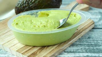 A spoon is being used to scoop out avocado from a container video