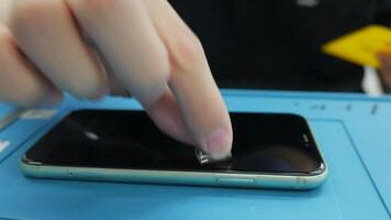 A person is using a small tool to clean the back of an iphone video