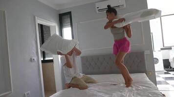 Engaging in an extremely fun and playful pillow fight in a bright and modern bedroom setting video