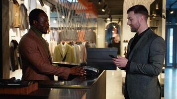 A Man at Counter Buys Shoes from Friendly Retail Sales Assistant, Paying with Contactless NFC Smartphone Touching Terminal video