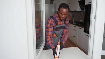 African american worker is applying polyurethane foam to fill gap between sash and window frame video