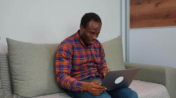 Black man talking to colleague team in call conference writing note on book with smile face. Man using computer laptop for online meeting video