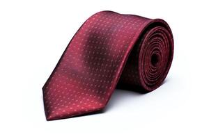A burgundy red tie with a dotted pattern. The tie is rolled up on a white background. photo