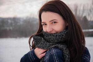 A smiling woman tossing snow into the air, wrapped in a thick scarf and coat, enjoying the winter weather in an open snowy field. Playful and carefree spirit of winter photo