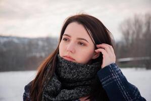 A close-up of a woman wearing a grey scarf and blue coat in a snowy outdoor setting, conveying a feeling of warmth and peacefulness in winter photo